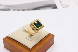 Close-up of golden Greek key engraved ring with square cut emerald green gemstone