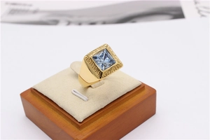 Macro shot of gold-plated meander ring featuring a square blue stone on a display stand