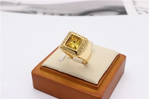 Macro shot of gold signet ring featuring square yellow gemstone and Greek key patterns
