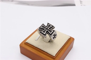 Macro view of vintage silver cross ring with black oxidized details on wooden stand