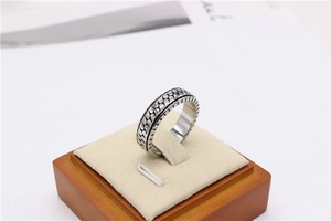 Detail of vintage silver spinner ring with a woven chain texture on a wooden stand