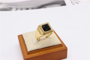 Macro shot of men's gold-plated square ring featuring black gemstone and Greek key pattern