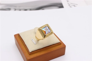 Macro detail of gold ring with square AB zircon stone and meander pattern engraving