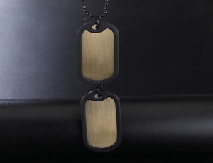 Macro detail of military dog tag pendant with brushed bronze finish and black silencer