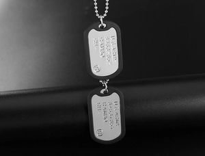 Detailed close-up of U.S. Army dog tag pendants with black silicone silencers on ball chain