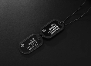 Detailed close-up of matte black U.S. Army dog tag necklace with engraved military text