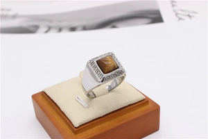 Macro detail of silver titanium ring with square tiger eye stone and Greek meander pattern