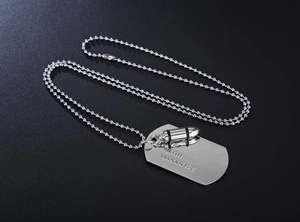 Detail of silver ball chain necklace with engraved dog tag and bullet pendant