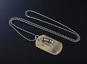 Dettaglio della collana con piastrina militare, incisione Rambo e ciondolo a proiettile