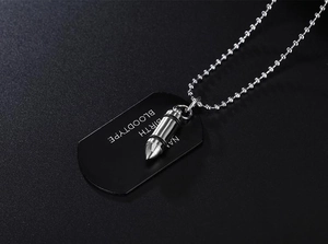 Macro shot of custom dog tag and silver bullet pendant necklace on matte black background