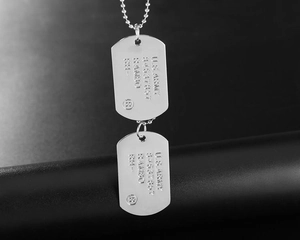 Macro view of dual U.S. Army dog tag pendants with brushed steel finish on a bead chain
