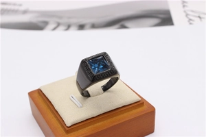 Detail of square blue stone and Greek key engraving on black stainless steel ring