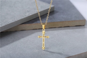 Detail of golden cross pendant with sunburst texture on minimalist stone background
