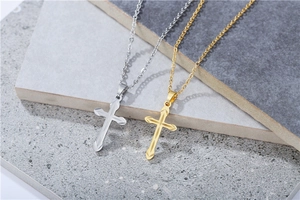Detailed view of silver and gold cross necklaces with embossed texture on stone surface