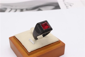 Detail of a men's black signet ring with red gemstone and Greek key patterns