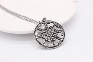 Vue macro détaillée du pendentif viking Kolovrat en argent rétro sur un plateau blanc