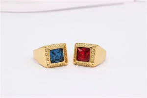 Detail view of gold signet rings featuring blue and red gems with Greca pattern borders