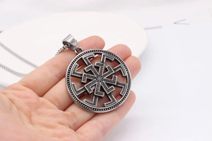 Gros plan détaillé du pendentif roue solaire Kolovrat slave au fini argenté
