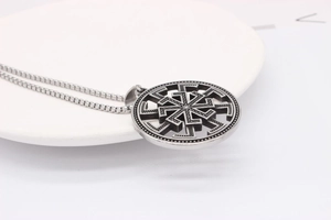 Détail du pendentif roue solaire Kolovrat argent vintage sur une chaîne en acier