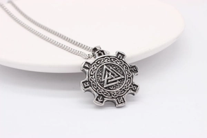 Macro shot of Viking Valknut gear pendant with Norse runes on polished stainless steel