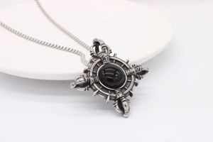 Detail of vintage silver cross pendant with a black onyx stone in a ceramic bowl