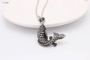 Close-up of vintage carp fish pendant with detailed scales and rustic silver finish