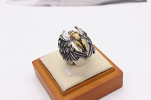 Macro detail of vintage silver wings with gold relief on men's titanium steel ring