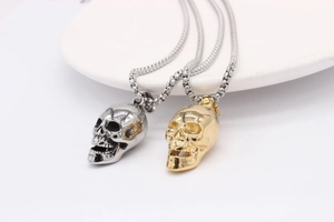 Close-up of gothic skull pendants in silver and gold finishes with steel box chains