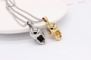 Macro detail of gothic skull pendants in gold and silver finish with steel box chains
