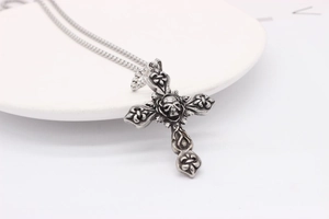 Detailed view of Gothic cross pendant with skull and flower engraving in retro silver finish