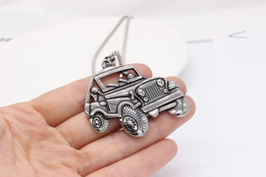 Detail of vintage silver off-road vehicle pendant showing intricate mechanical carving