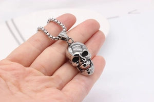 Macro shot of stainless steel skull pendant with realistic bone texture on box chain