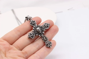 Macro view of retro skull cross pendant with floral relief in antique steel finish