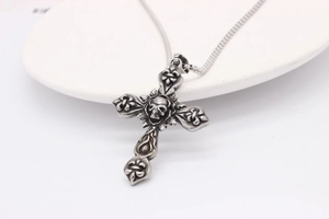 Detailed view of Gothic silver cross pendant with skull and vintage floral relief