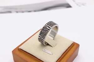 Macro detail of men's silver stainless steel ring with rustic tree bark texture finish