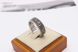 Macro detail of men's titanium steel ring with unique bark texture on a wooden stand