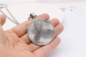 Detail of silver round shield pendant back with honeycomb mesh pattern on chain