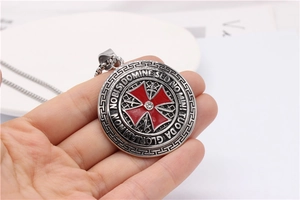 Detailed close-up of retro silver cross shield pendant with red enamel and white crystal