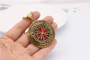 Macro detail of gold vintage templar cross necklace with red inlay and white diamond