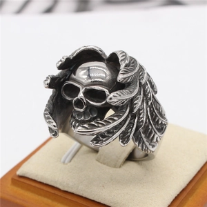 Retro gothic skull ring with feathered wings in distressed silver steel on a wooden stand