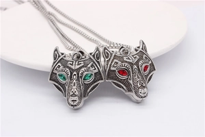 Detailed close-up of retro wolf head pendants with green and red gem eyes in steel