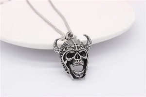 Macro shot of punk bull skull pendant with horns and cross engraving on a white tray