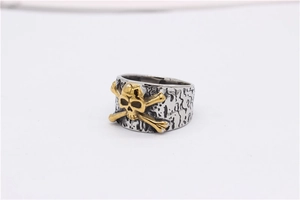 Detail of vintage silver textured band featuring golden skull and crossbones design