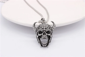 Close-up of retro silver skull pendant with horned helmet and cross detail on chain