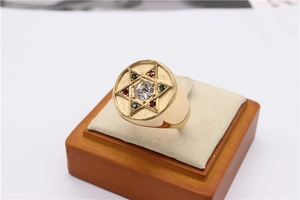 Gros plan d'une bague hexagramme dorée avec des pierres rouges, vertes et transparentes