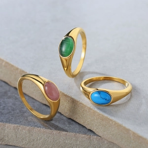 Dettaglio di tre anelli dorati vintage con pietre occhio di gatto verdi, rosa e blu