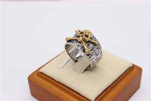Close-up of retro punk skull and crossbones ring in gold and silver stainless steel