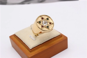 Détail d'une bague chevalière étoile dorée sertie de zircons rouges, verts et blancs