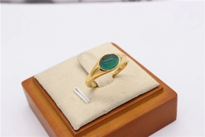 Dettaglio di un anello a sigillo dorato con una pietra occhio di gatto verde ovale lucida