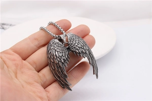 Macro shot of retro silver angel wing pendant with detailed feathers and square pearl chain